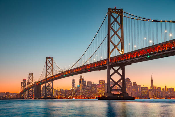 skyline von san francisco mit oakland bay bridge bei sonnenuntergang, kalifornien, usa - san francisco bay golden gate bridge bridge san francisco county stock-fotos und bilder