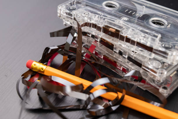 istock Audio cassette and pencil on a black table. Old magnetic data carrier. Dark background. 1090557768