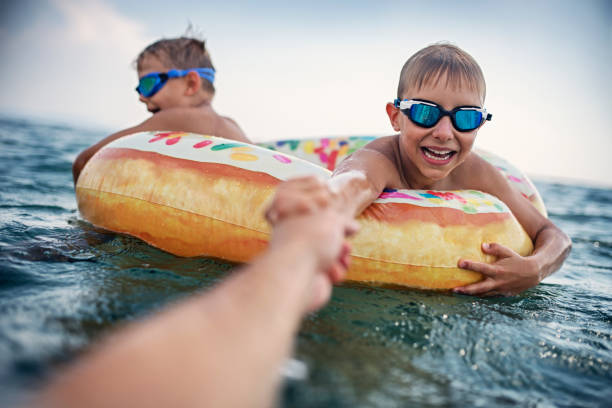 petits garçons jouant dans la mer sur l’anneau de bain - child nautical vessel summer swimming goggles photos et images de collection