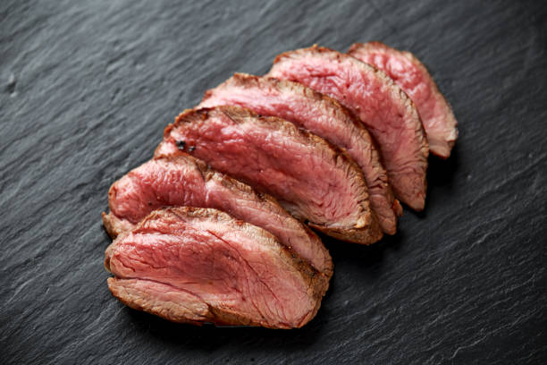 filete de venado raro medio en rústico tablero de piedra oscuro - carne de caza fotografías e imágenes de stock