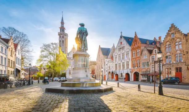 Scenic view of historical Brugge city center with famous Jan van Eyck square in beautiful golden evening light, Flanders region, Belgium