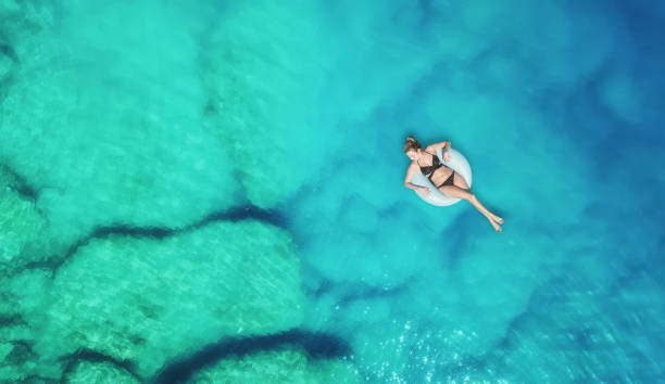 blick auf das mädchen auf der meeresoberfläche. schöne komposition im sommer - swim ring stock-fotos und bilder