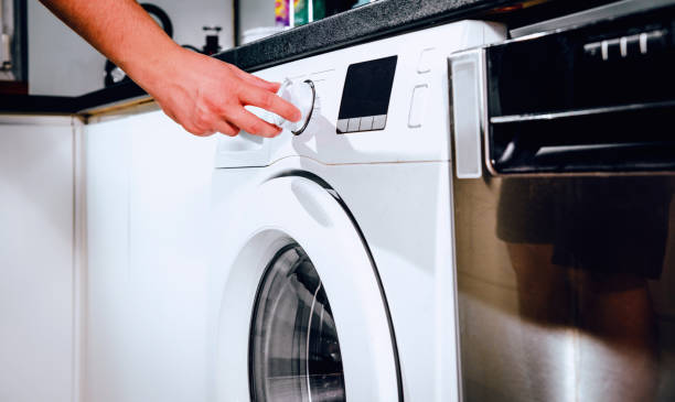 Doing the laundry. The man presses the start of the washing machine. Man does the washing in washing machine. Cleaning clothes. Unusual role of a man in role of a woman. tumble dryer stock pictures, royalty-free photos & images