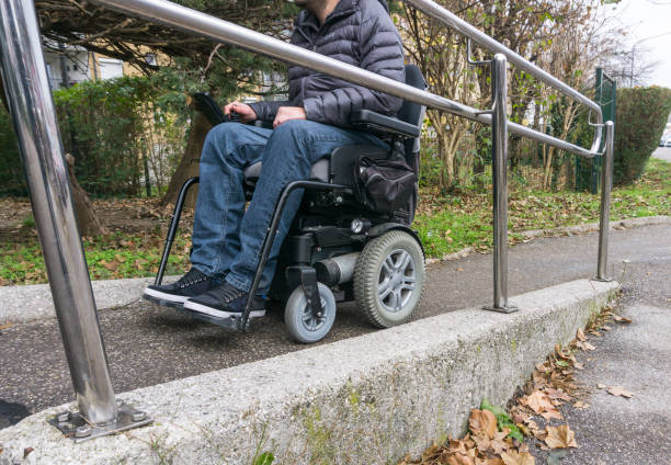 istock Man in a wheelchair using a ramp next to stairs 1090606280