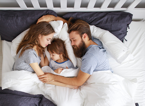 happy family mother, father and  father child daughter r sleeping in bed
