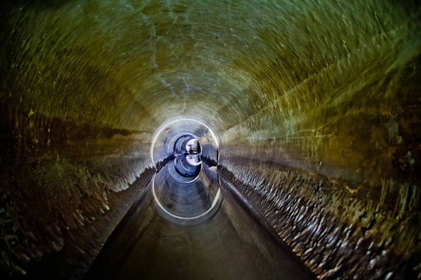 Flooded round sewer tunnel is reflecting in water.