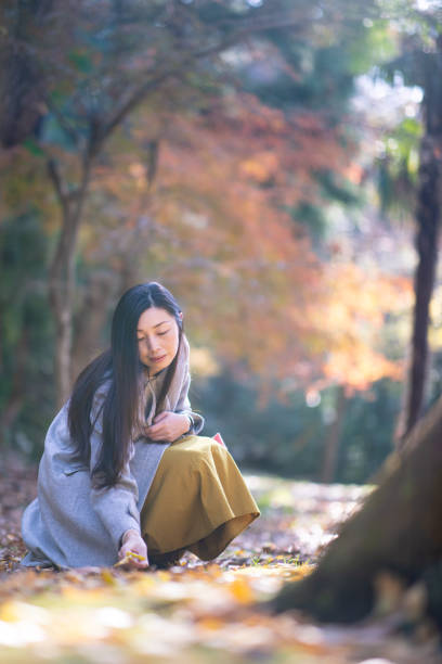 istock Woman picking up fallen leaves in autumn forest 1090610468