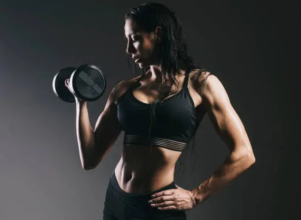 fit woman with barbell front of the grey background