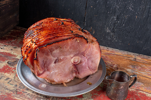 Spiral-cut baked glazed ham on rustic painted table