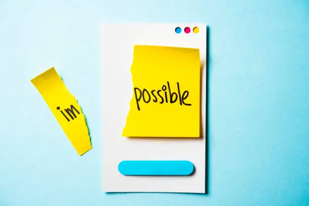 Photo of Impossible is possible note with paper smart phone concept on blue background.