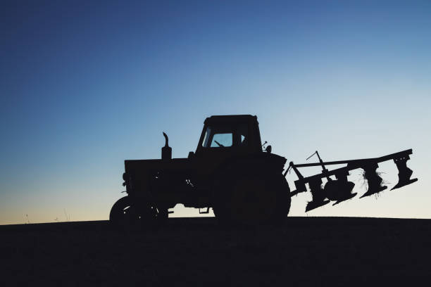 istock Tractor on the field. Silhouette against a blue sky 1090613204