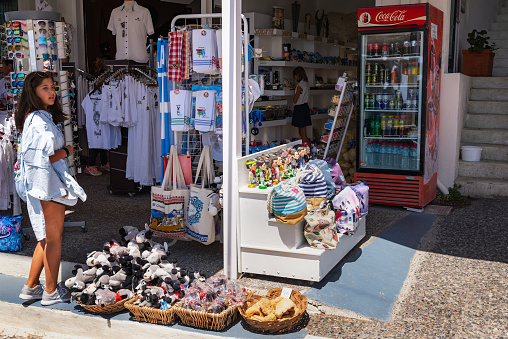 Santorini, Greece - August 2018: Young girl is bying souvenirs at small gift shop.