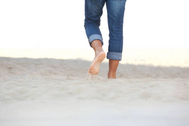 istock male feet walking barefoot on sand at the beach 1090648380