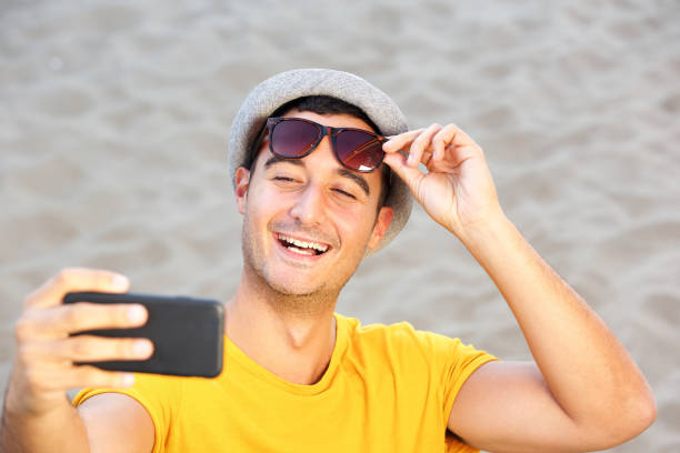 istock happy man with hat and sunglasses taking selfie at the beach 1090648392