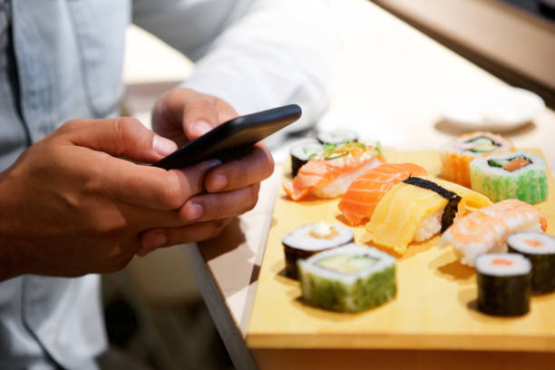 istock Close up hands with smart phone at sushi bar 1090648624