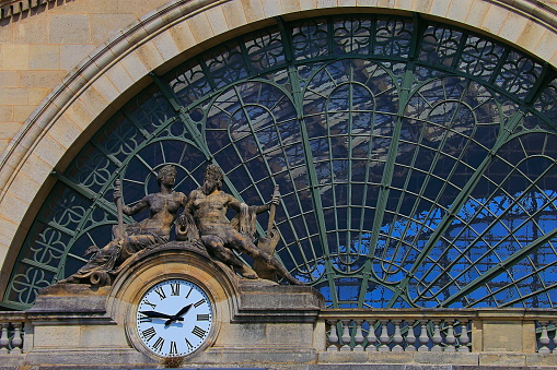 Gare du Nord with clock and glass ornate facade details - Paris, France

The Gare du Nord (North Station), officially Paris-Nord, is one of the six large terminus stations of the SNCF mainline network for Paris, France. Near Gare de l'Est in the 10th arrondissement, the Gare du Nord offers connections with several urban transport lines, including Paris Métro, RER and buses. 

By the number of travellers, at around 214 million per year, it is the busiest railway station in Europe, the 24th busiest in the world and the busiest outside Japan.

The Gare du Nord is the station for trains to Northern France and to international destinations in Belgium, Germany, the Netherlands, and the United Kingdom. The station complex was designed by the French architect Jacques Hittorff and built between 1861 and 1864.