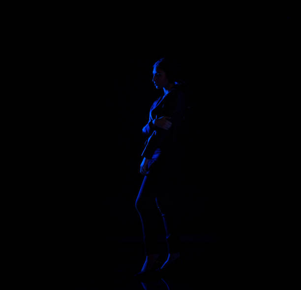 istock Attractive latino female standing in the dark with blue light on her 1090670612