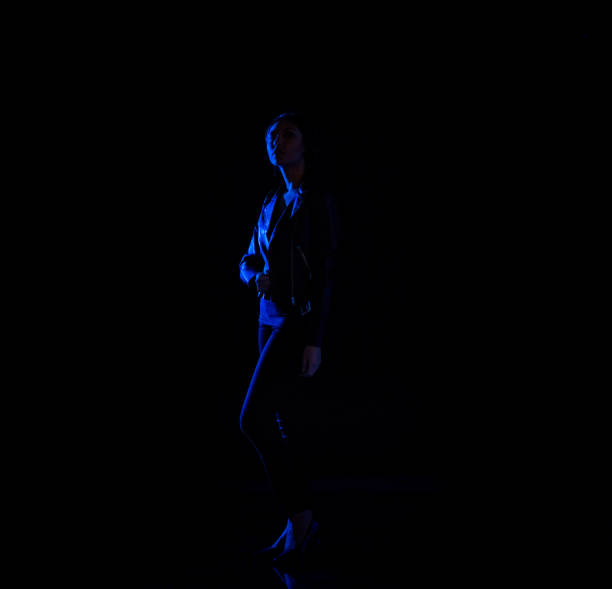 istock Attractive latino female standing in the dark with blue light on her 1090670614