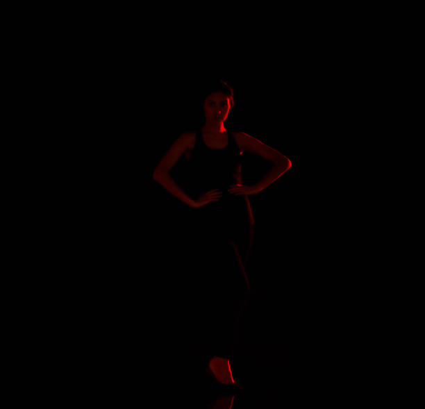 istock Attractive latino female standing in the dark with red light on her 1090670628