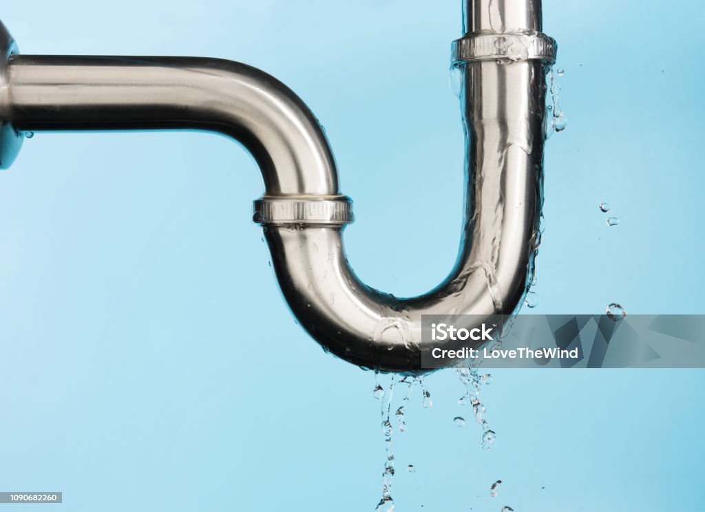 Leaking of water from stainless steel sink pipe on isolated on light blue background Leaking Stock Photo