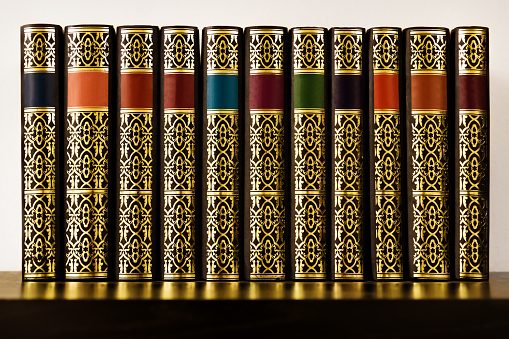 Antique looking books with golden decoration and colorful bands on a shelf