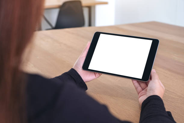 istock a woman holding and looking at black tablet pc with blank white screen while sitting in office 1090709686
