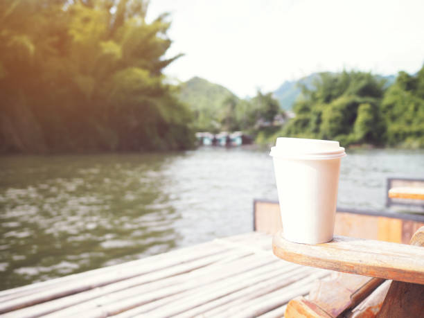 take away coffee cup on the chair at the resort nearby the river in the morning.