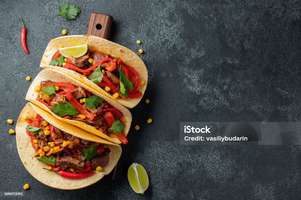 Tacos messicani con manzo, verdure e salsa. Tacos al pastor su tavola di legno su sfondo nero. Visualizzazione dall'alto con spazio di copia - Foto stock royalty-free di Taco