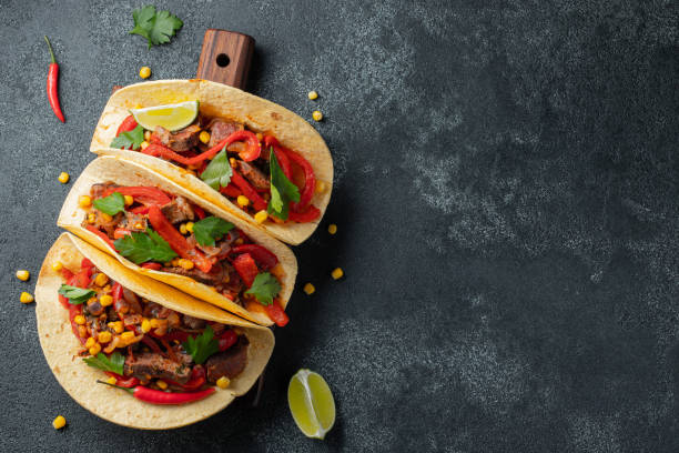 Mexican tacos with beef, vegetables and salsa. Tacos al pastor on wooden board on black background. Top view with copy space Mexican tacos with beef, vegetables and salsa. Tacos al pastor on wooden board on black background. Top view with copy space. mexican food stock pictures, royalty-free photos & images