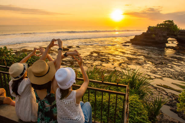 Happiness tourist with beautiful view of Pura Batu Bolong at sunset. Bali, Indonesia : July-15-2018 : Happiness tourist enjoy their holiday with the beautiful sunset over Pura Batu Bolong an iconic Hinduism sea temple in Bali, Indonesia. tanah lot sunset stock pictures, royalty-free photos & images