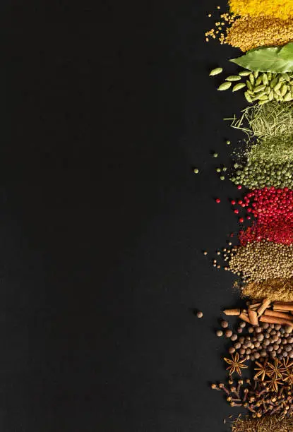 Photo of Indian condiments on black table in high resolution. Spices for cooking food on background of chalkboard with empty space.