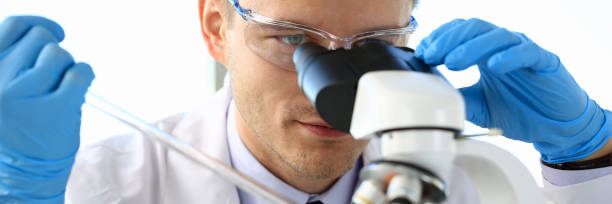 portrait of a young chemist looking in binocular - lubrication infection imagens e fotografias de stock