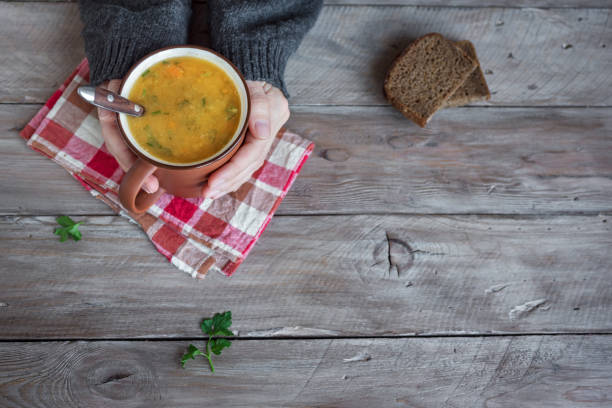 istock Mug of soup in hands 1090744594