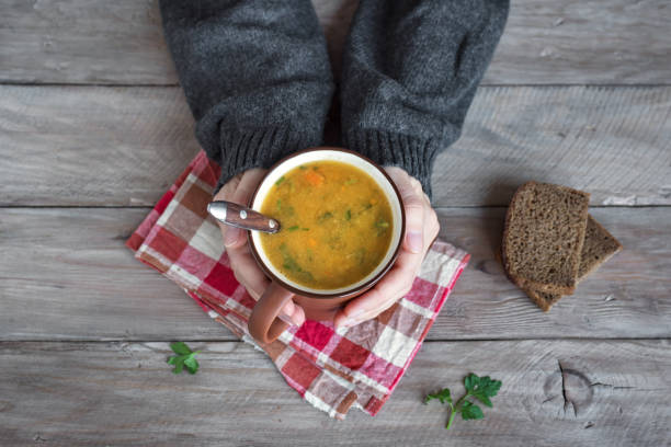 istock Mug of soup in hands 1090744604