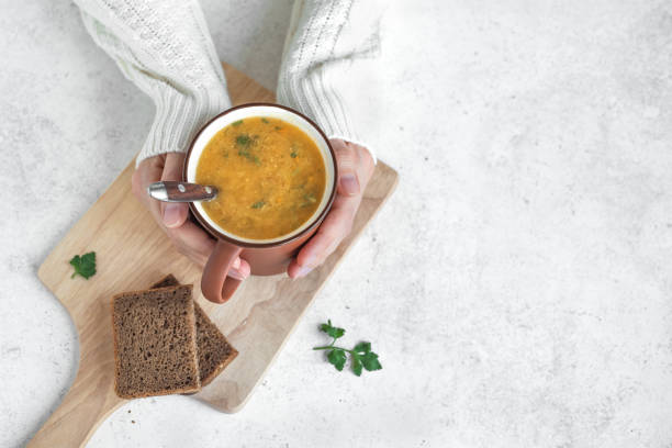 istock Mug of soup in hands 1090744608