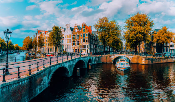 панорама амстердама. знаменитые каналы и мосты при теплом дневном свете. нидерланды - amsterdam стоковые фото и изображения