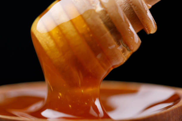 istock Honey flowing down from a honey spoon on a dark background. Macro. 1090757818