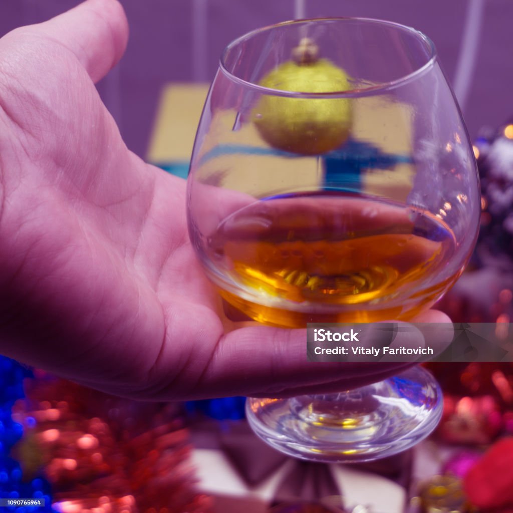 Cropped shot of four people clinking glasses with red wine over wooden table with fairylights and merry christmas card Cropped shot of four people clinking glasses with red wine over wooden table with fairylights and merry christmas card . Alcohol - Drink Stock Photo