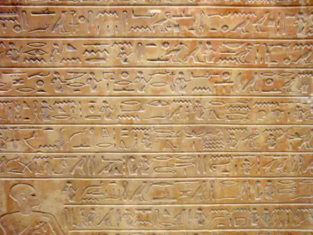 Texture of hieroglyph in light brown stone for background.