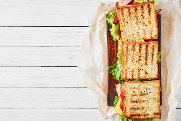 istock Three sandwiches with ham, lettuce and fresh vegetables on a white background, top view with copy space 1090773056