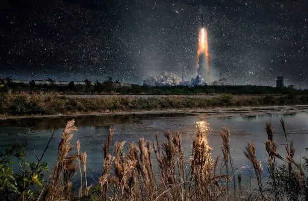 Photo of Missile launch at night. Tranquil nature landscape and reflection in the creek. The elements of this image furnished by NASA.