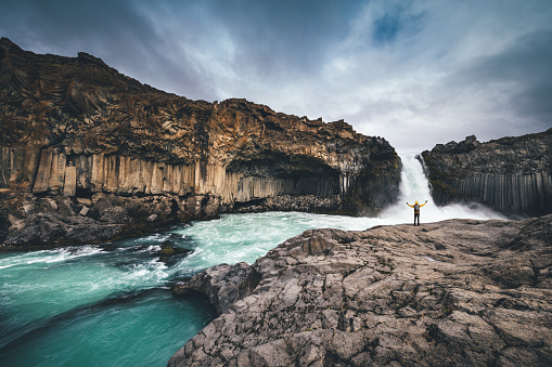 Man exploring Aldeyjarfoss waterfall surroundings in Iceland.