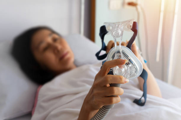Obstructive sleep apnea therapy. Senior patient woman hands holding Cpap mask  lying  in hospital room. sleep apnea photos stock pictures, royalty-free photos & images