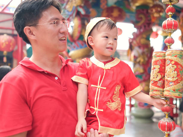 アジア家族祝う中国新年、ローカル中国の寺院で伝統的な赤の中国スーツの小さな 2 歳の幼児男の子子供はかわいい - chinese ethnicity chinese culture china 2 3 years ストックフォトと画像