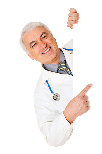 Doctor holding blank sign showing something by his index finger, isolated on white. You can add extra white space with your message to the right.