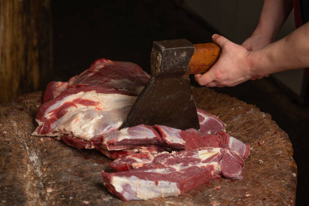 a butcher is chopping beef with an axe