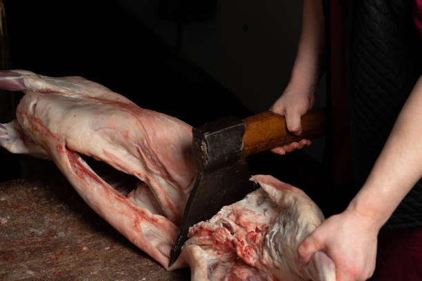 Butcher chopping lamb with an axe on the chopping board