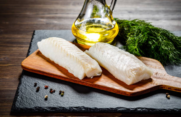 fresh raw cod fillet on cutting board - bacalhau imagens e fotografias de stock