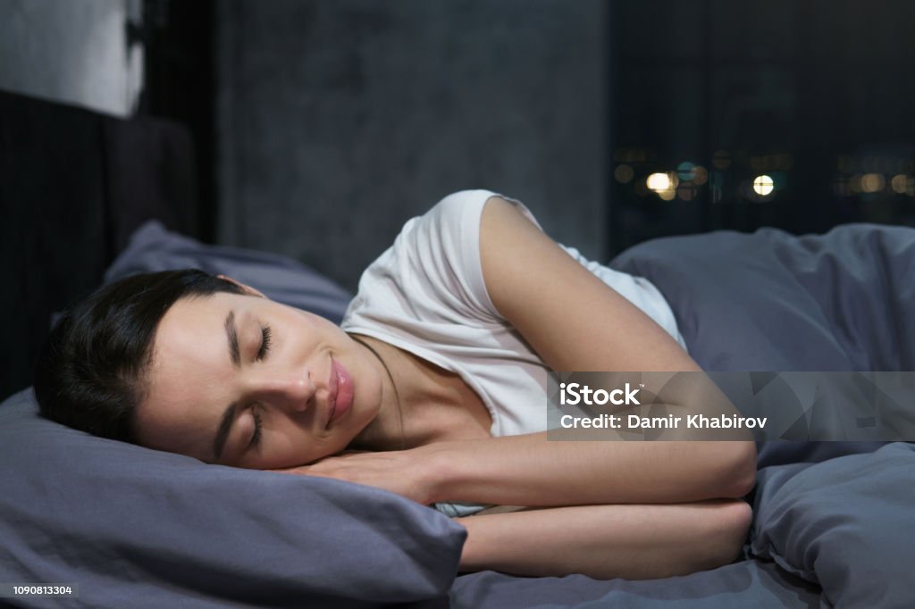Jonge vrouw slapen rustig in haar slaapkamer 's nachts, ontspannen - Royalty-free Slapen Stockfoto