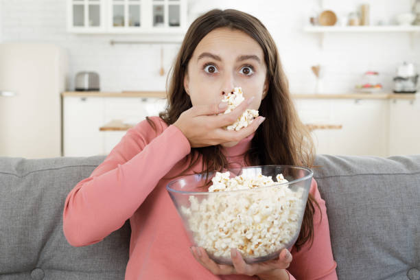 istock Lady eating popcorn while looking at TV screen, completely absorbed with plot and what is going on 1090813320